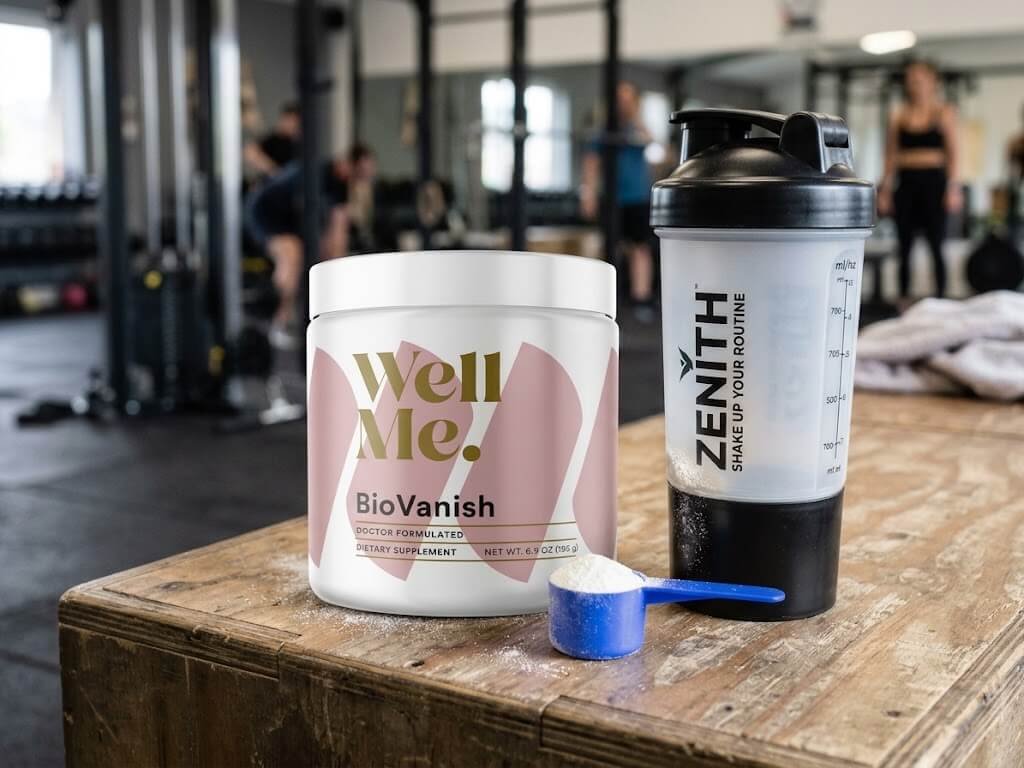 Close-up of a BHB powder scoop and a tub next to a shaker bottle on a gym counter
